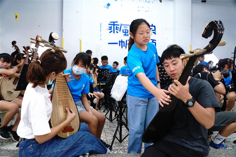 觀眾體驗彈琵琶。家長回應說：我夢想彈琵琶，今天美夢成真。