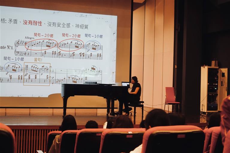 林姿茵現場彈奏示範並以譜例為輔為學生進行音樂不同詮釋的解說（地點：台中二中演奏廳）