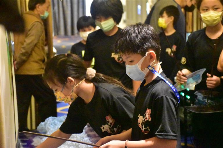 學生測試皮影戲戲偶，並趁正式演出前試著操偶、練說台詞、測試音效等。