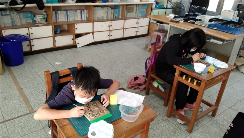 學生專心修整陶板細節