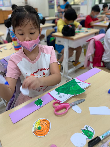 學生將頭套裝飾剪下並貼上頭套